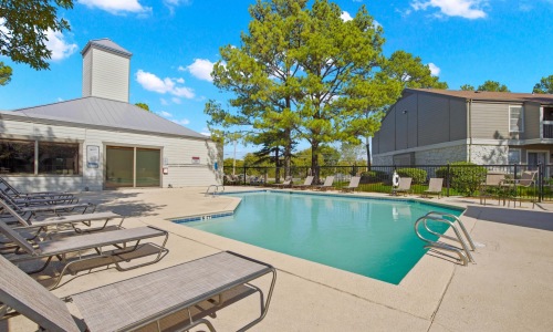 A pool with chairs around it at Eagle Point pet-friendly apartments in Tulsa.
